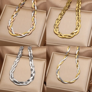 Flat braided snake chain necklaces in gold and silver colors on champagne jewelry boxes