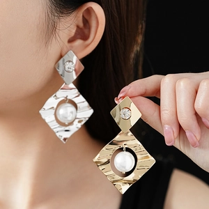 Detailed view of geometric diamond pearl earrings with hammered metal and crystal studs