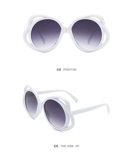Detail view of white butterfly oval sunglasses with grey gradient lenses and hollow frame
