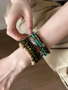 Détail de bracelets bohèmes en perles de bois avec des breloques argentées gravées