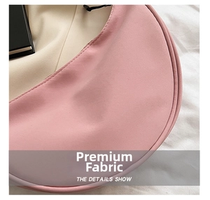 Detail of pink nylon dumpling bag showing smooth fabric texture and curved crescent shape