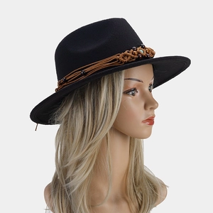 Détail d'un chapeau en laine noir avec ruban tressé marron et perle de turquoise