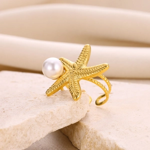 Detailed macro view of a gold starfish ring with a pearl on natural stone display