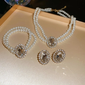 Detailed view of luxury pearl necklace set with crystal pendants in a gold metal tray