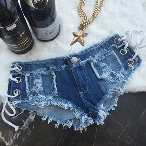 Dettaglio di hot pants in denim blu con lacci laterali e bordi sfrangiati su tappeto morbido