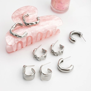Detail of silver C-shaped earrings with smooth, hammered, and pleated textures in set