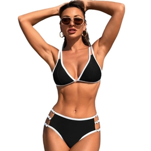 Two-piece black bikini with white trim, high waist, and metallic ring side cutouts