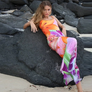 Detail of vibrant floral print dress with backless slit design on a rocky beach
