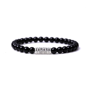 Détail de perles en pierre naturelle noire de 6 mm avec un charme mantra en argent vieilli