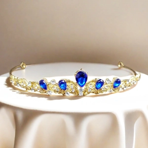 Macro detail of luxury golden crown featuring teardrop blue gems and sparkling crystals