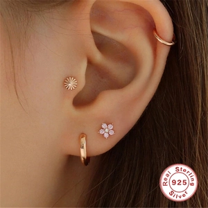 Detailed view of sterling silver flower studs and gold hoop earrings on ear