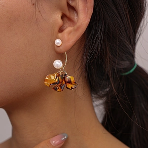 Detail view of the floral earring with acrylic petals and pearls on a model ear