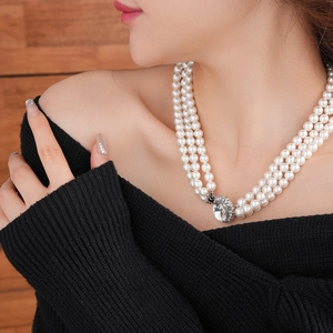 Dettaglio ravvicinato della collana di perle a più strati con elegante chiusura ovale