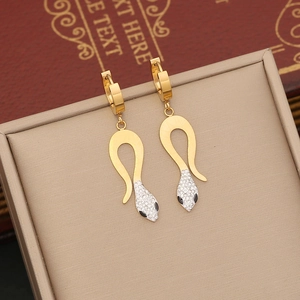 Detail of gold snake earrings with white crystals on a luxury vintage background