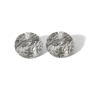 Detailed view of silver round stud earrings with irregular embossed texture on white background