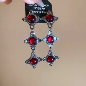 Detailed view of S925 silver long drop earrings with three vertical red round stones