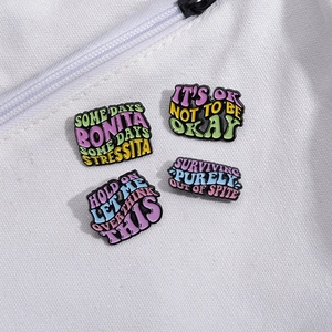 Colorful enamel pins with motivational quotes displayed on a white canvas backpack