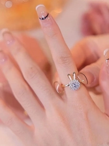 Detail eines drehbaren Hasenrings mit Zirkonia an der Hand in warmer Umgebung