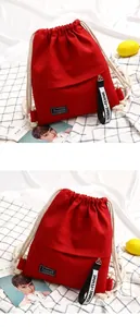 Close-up of a red canvas drawstring backpack with a black Fashion label and white cotton ropes