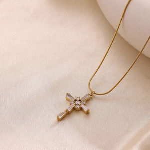 Exquis collier croix dorée avec zircons clairs sur fond élégant en soie champagne