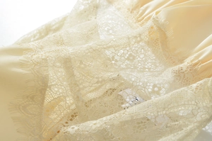 Makroansicht der Wimpernspitze und des Satinstoffs am beigen Neckholder-Kleid