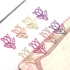 Tulip shaped metal paper clips in purple and pink displayed on a notebook page