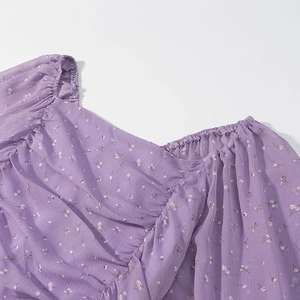 Dettaglio dello scollo quadrato e del tessuto in chiffon floreale sul mini abito viola