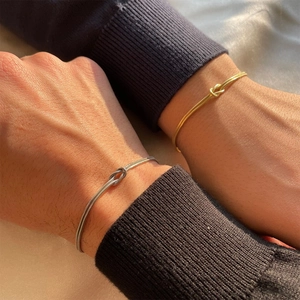 Matching gold and silver knotted snake chain bracelets for couples on wrists