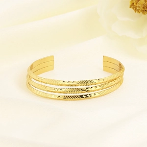 Detailed close-up of a triple-layered gold stainless steel cuff with geometric textures