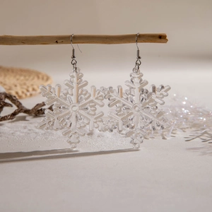 Detailed view of resin snowflake earrings hanging on a branch in a winter setting