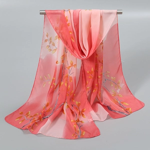 Détail d'une écharpe en mousseline rose dégradé avec motif de feuilles sur barre