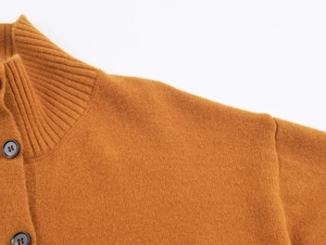 Détail d'un cardigan en tricot caramel avec col montant et boutons ronds foncés