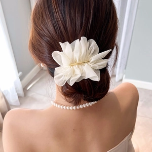 Detailed back view of an elegant white chiffon flower hair clip on a low bun hairstyle