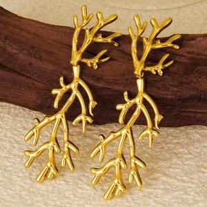 Detailed view of gold plated branch earrings with smooth polished finish on wood