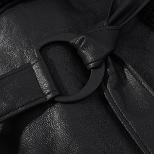 Detail of metal ring buckle and smooth black leather strap on a stylish coat