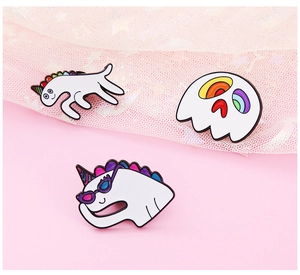 Close-up of enamel unicorn pins with rainbow mane and ghost design on pink mesh fabric