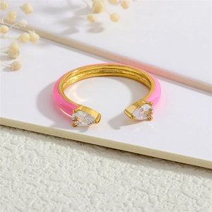Macro shot of gold adjustable ring with pink enamel coating and pear-shaped zircon stones