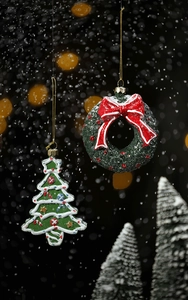 Detailed view of hand-painted Christmas wreath and tree ornaments with festive bokeh background