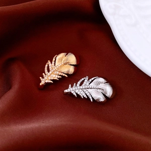 Detailed close-up of feather brooches with 18k gold plating and sparkling zircon stones