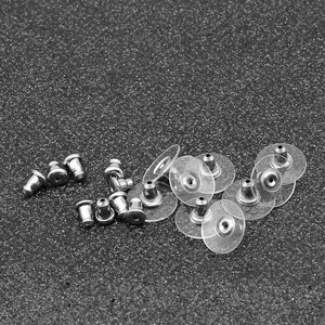 Mix of stainless steel butterfly earring backs and clear plastic disc stoppers on black background