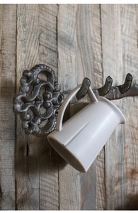 Detail of vintage cast iron wall hook with scroll motif holding a ceramic mug