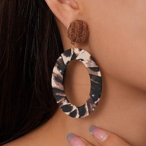 Close-up of fabric leopard print oval earrings with rhinestones on fashion model