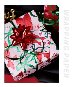 Detail of pink Christmas wrapping paper with red bow patterns and festive ribbons