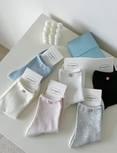 Detail of cream-style socks with pink shell buttons and knitted texture in pastel colors