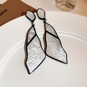 Macro shot of geometric acrylic dangle earrings with silver needle on white tray