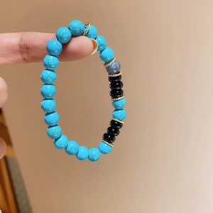 Detail of beaded bracelet with blue turquoise, black onyx, and gold gear spacers