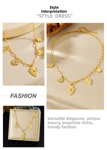 Close-up of gold paperclip chain necklace with arrow, flower, and wing charms