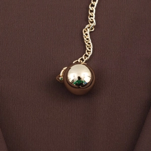 Elegante goldene Metallkette mit polierten Rundkugeln auf dunklem Stoffgewebe