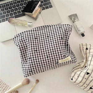Gros plan d'une trousse à maquillage à carreaux sur un bureau avec des pinceaux