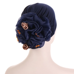 Detail of navy blue turban hat featuring handcrafted flower with gold roses and orange rhinestones